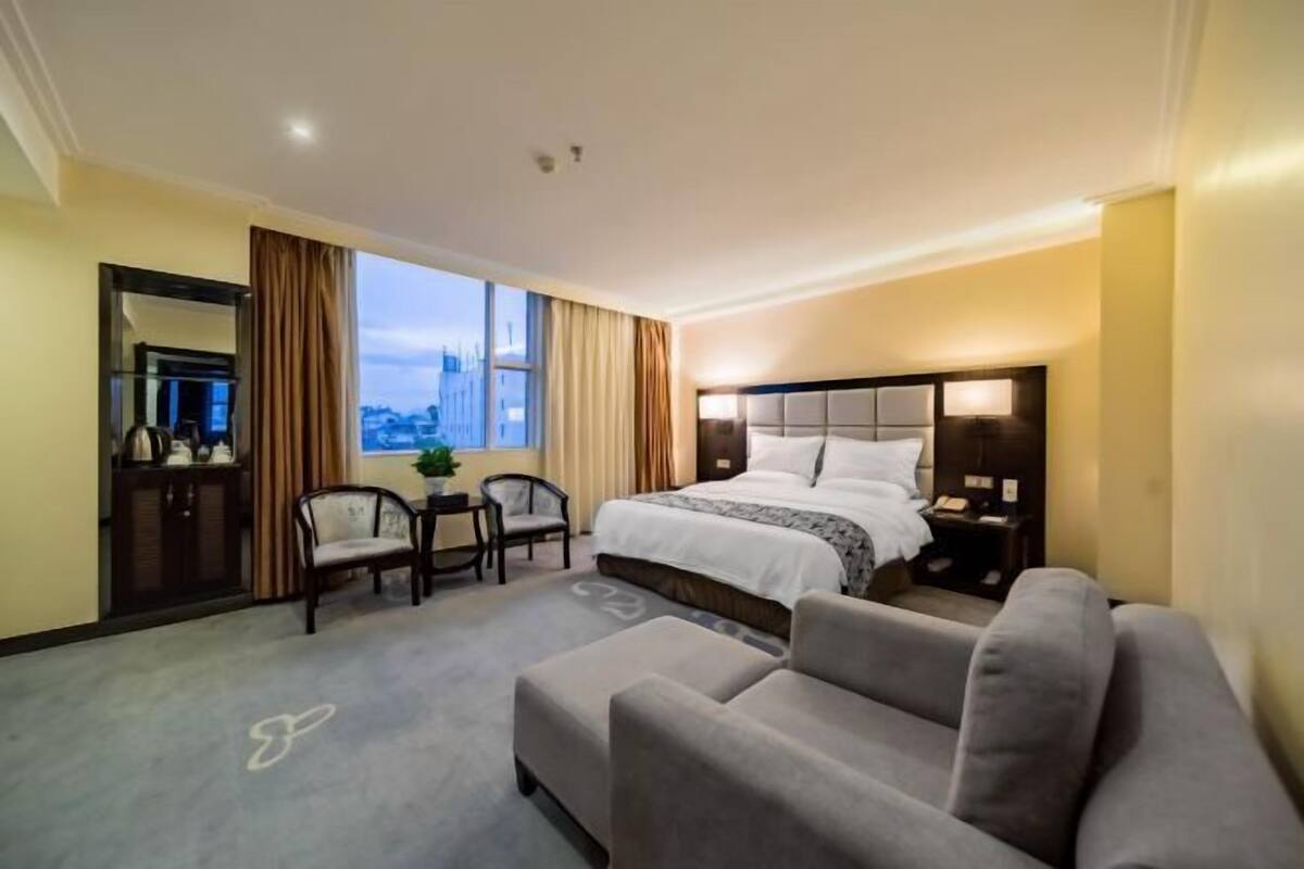 A hotel room with a bed, a sofa, a desk, and a chair.