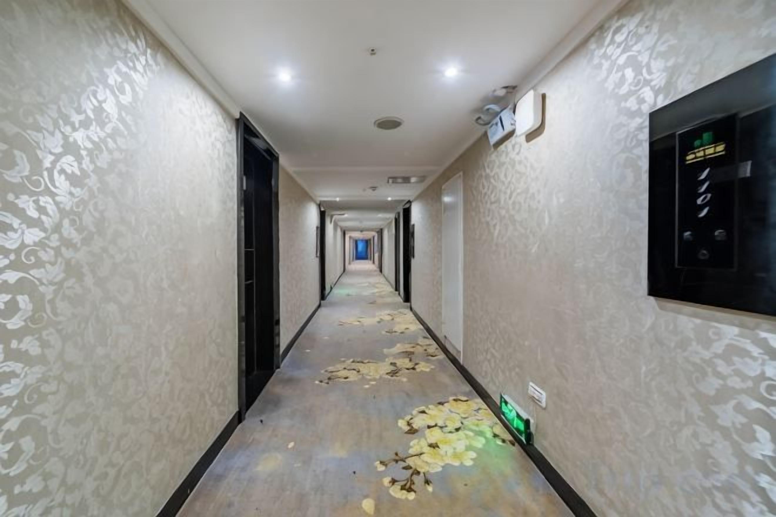 Un pasillo de hotel con paredes estampadas, una larga galería y un panel de control en la pared derecha.