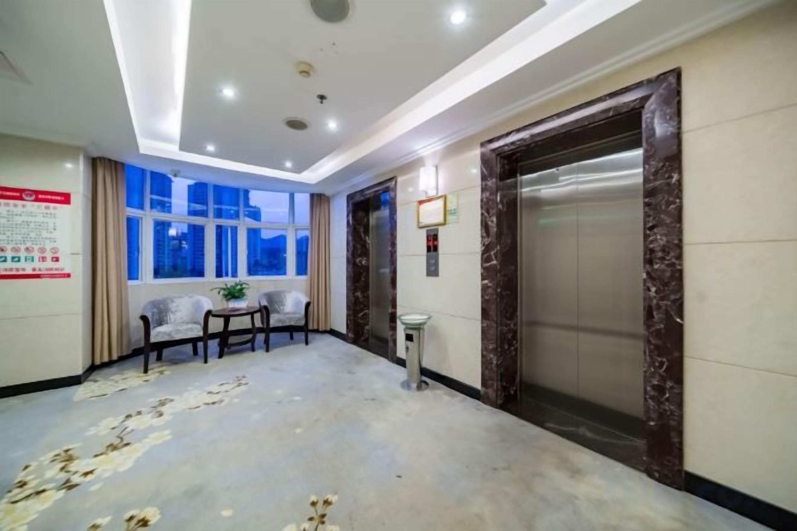 A hotel lobby with an elevator, a reception desk, and a seating area.