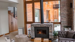 Amplia sala de estar con chimenea, ventanas grandes y techo alto.