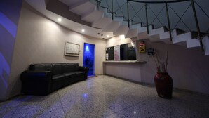 A modern interior with a curved staircase, a black leather sofa, a red vase, and a blue-lit door. - Hotel y Villas Vento (Ecatepec de Morelos)