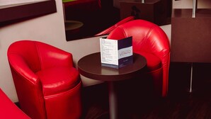 A red leather chair and a small table with a menu in a modern interior. - Hotel y Villas Vento (Ecatepec de Morelos)