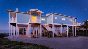 A beachfront house with multiple decks and a balcony, featuring a staircase leading to the upper levels. - The Blue Marlin - Beachfront Oasis with Private Beachside Pool & Boat Dock (Captiva)