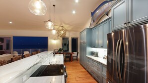 A modern kitchen with a large island, stainless steel appliances, and a view of the ocean. - The Blue Marlin - Beachfront Oasis with Private Beachside Pool & Boat Dock (Captiva)
