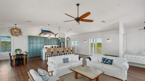 A spacious living area with a white sofa set, a coffee table, and a dining table with chairs. - The Blue Marlin - Beachfront Oasis with Private Beachside Pool & Boat Dock (Captiva)