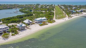 An aerial view of a coastal property with multiple buildings, a beach, and a marina. - The Blue Marlin - Beachfront Oasis with Private Beachside Pool & Boat Dock (Captiva)