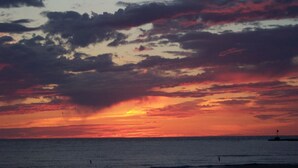 A sunset over the ocean with a lighthouse in the distance. - Downtown St. Joe! Walk to BEACH & EVERYTHING! Clean & Comfortable!  Best Value! (St. Joseph)
