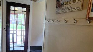 A hallway with a welcome sign, a door, a rug, and a wall-mounted hook system. - Downtown St. Joe! Walk to BEACH & EVERYTHING! Clean & Comfortable!  Best Value! (St. Joseph)
