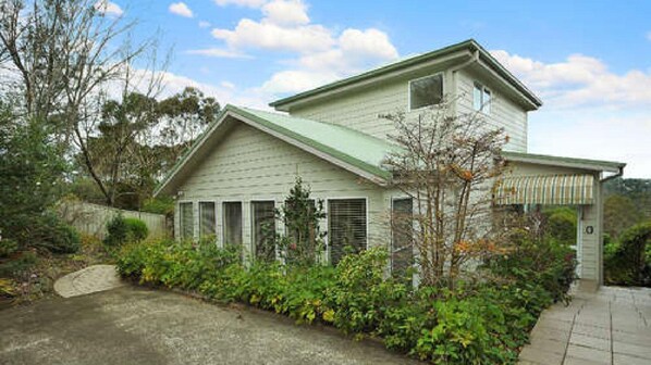 A two-story house with a green roof, a front porch, and a driveway. - Tranquility Large Mountain Home With Views (KATOOMBA)