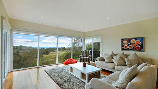 A spacious living room with a large sliding glass door leading to a scenic outdoor view. - Tranquility Large Mountain Home With Views (KATOOMBA)