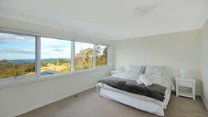 A bedroom with a large window, a bed, a bedside table, and a nightstand. - Tranquility Large Mountain Home With Views (KATOOMBA)