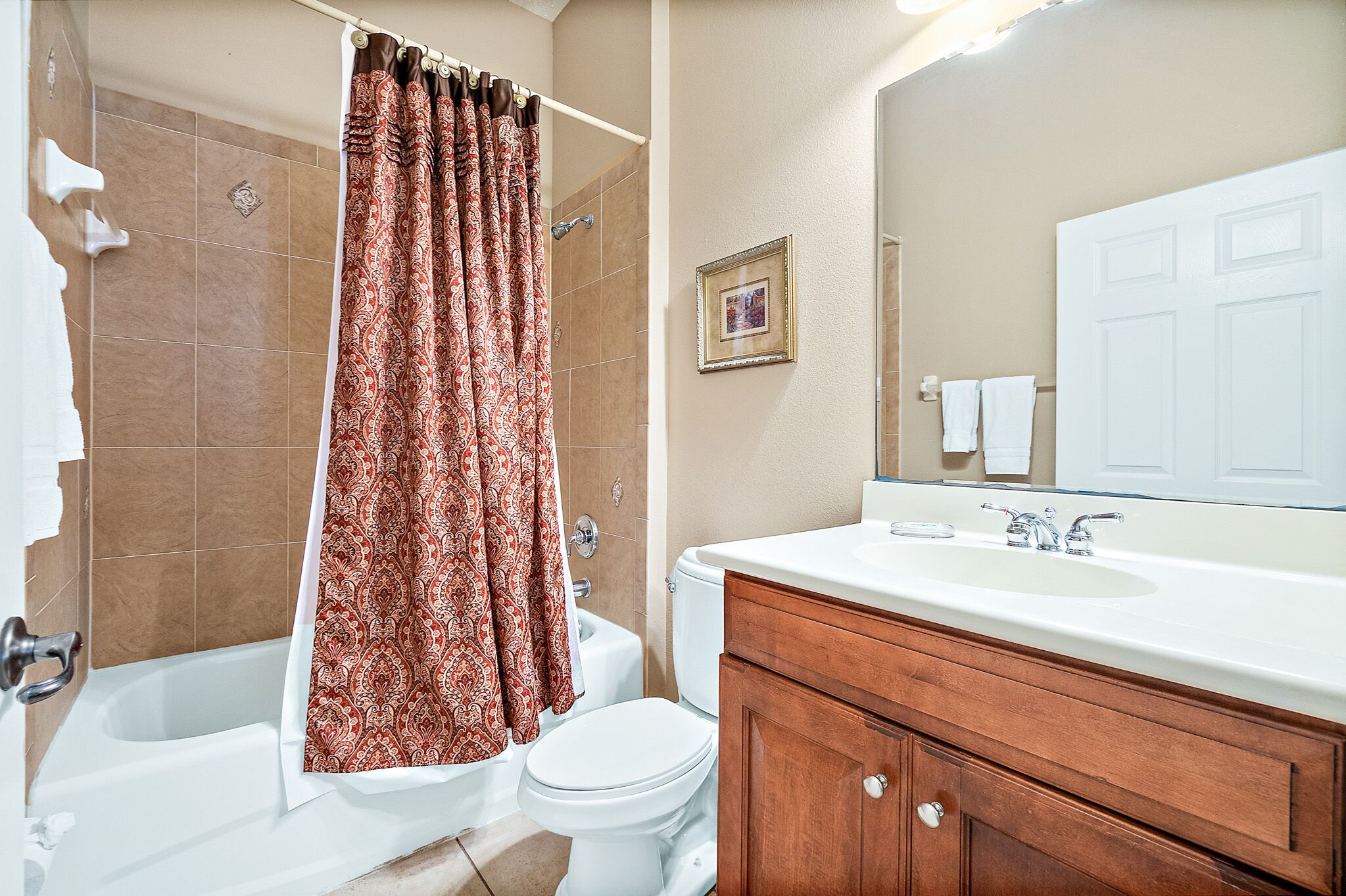 Baño con bañera, inodoro y tocador con espejo.