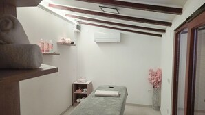 Una stanza piccola e pulita con un letto singolo, uno scaffale con articoli da toilette e un tavolino con un asciugamano.