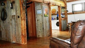 Un interior rústico con vigas de madera, una zona de entrepiso y un sofá de cuero con revistas.