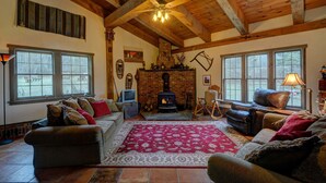 Un salón acogedor con chimenea, vigas de madera y ventanas amplias.