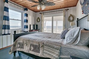 Relax in this ocean-view bedroom with a large bed, ceiling fan, and television.