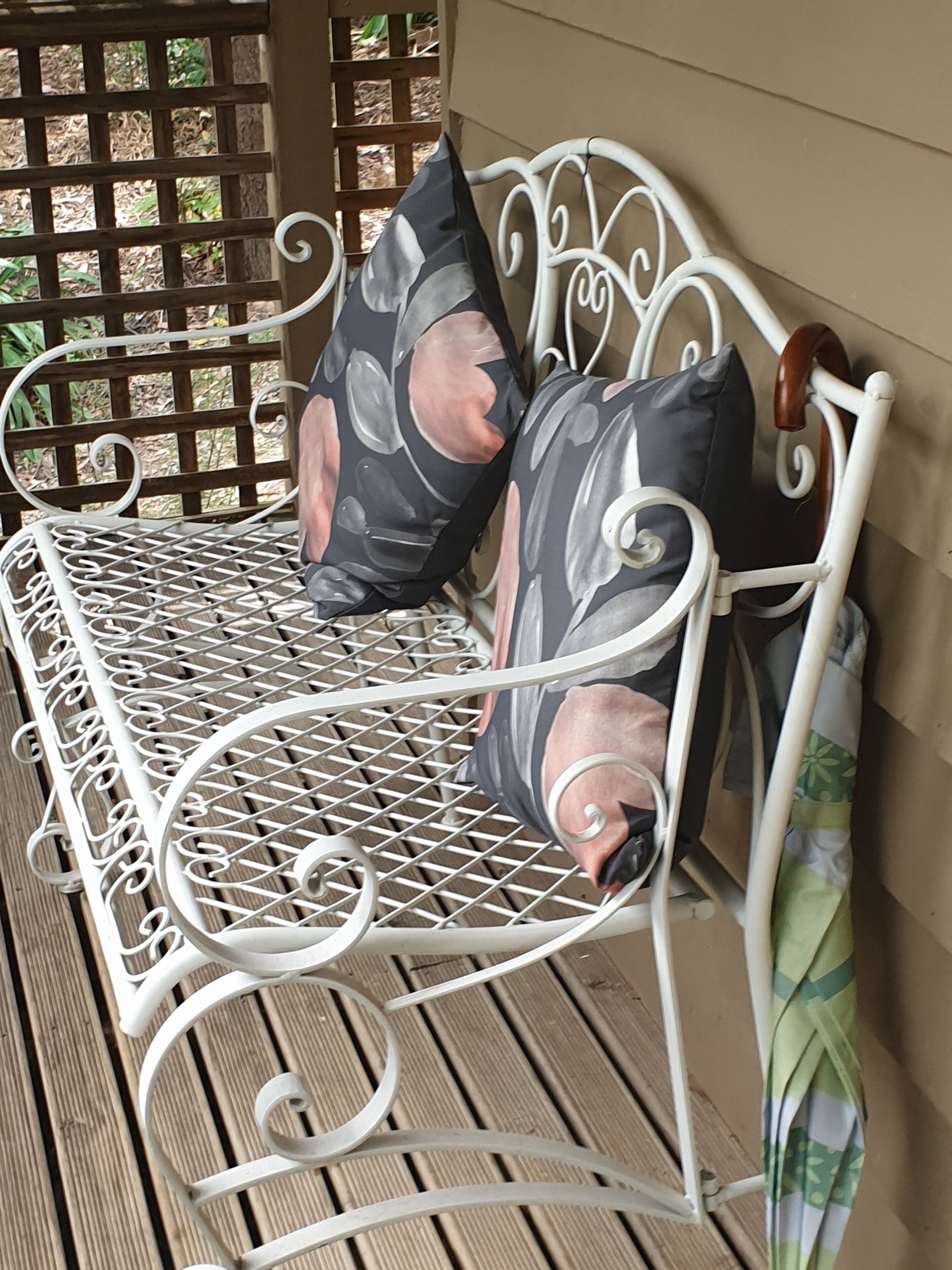 Een dagbed met metalen frame, een houten lattenbodem, twee kussens en een houten hoofdbord.