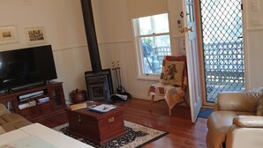A living room with a TV, a fireplace, a sofa, and a dining table. -  ASTLEY  COTTAGE   SPA & KING BED WITH FREE  WIFI & Netflix (Daylesford)