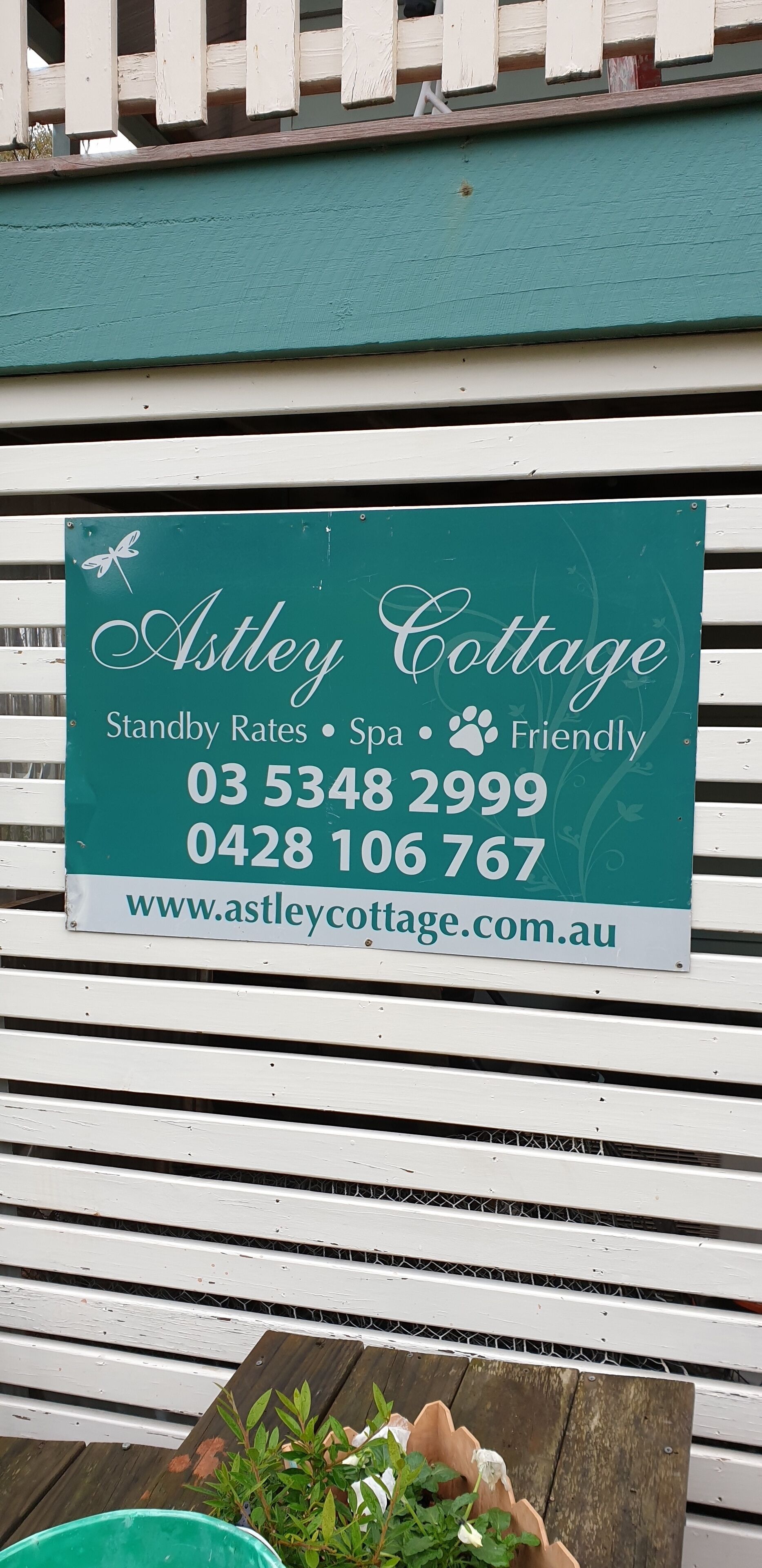 Segnaletica per Astley Cottage, che indica tariffe flessibili, spa e ambiente accogliente, con numeri di contatto e indirizzo web.