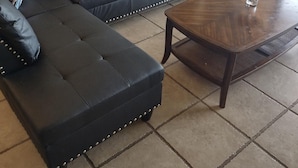 A living room with a sectional sofa, a wooden coffee table, and patterned cushions.