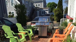 A wooden deck with outdoor seating and a barbecue grill.
