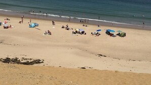 Ein Strand mit badenden Personen, Sonnenschirmen und Zelten.