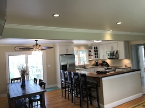 Una cocina moderna con armarios blancos, una isla central y un comedor con mesa y sillas de madera.