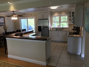 A modern kitchen with white cabinets, a granite countertop, a built-in refrigerator, and a window with a view of greenery. - Montauk Beach House Walking Dist to Private Beach&Montauk Harbor Restaurants (Montauk)