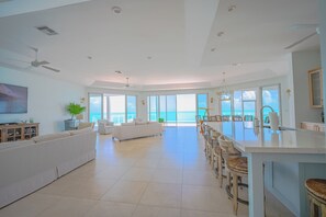 Amplia sala de estar con un sofá grande, comedor con sillas y cocina con barra.