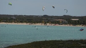 Una platja amb diversos pilotes geomètriques volant al cel.