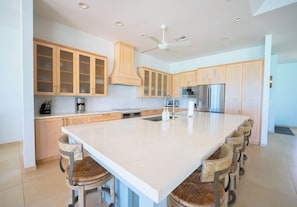 Una cocina moderna con una isla grande, muebles de madera, electrodomésticos de acero inoxidable y un ventilador de techo.