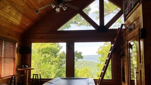 A wooden cabin room with a bed, a ceiling fan, a TV, and a view of the outdoors. - Bears Abound-- a Dog-friendly, Log Cabin With Breathtaking Views (Sevierville)