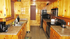 A wooden cabin kitchen with granite countertops, stainless steel appliances, and a bear-themed rug. - Bears Abound-- a Dog-friendly, Log Cabin With Breathtaking Views (Sevierville)