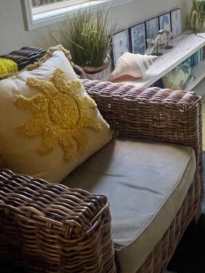 A wicker sofa with a cushion, a small potted plant, and a framed picture on a shelf. - Beachhouse on Seabrae -SO close to BEACH and ESTUARY- Pet Friendly  (Pottsville)