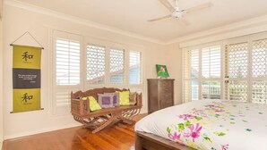 Un dormitorio con cama, banco de madera, armario y ventilador de techo.
