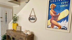 Una habitación con una mesa consola de madera, un cartel enmarcado y un letrero colgado en la pared.