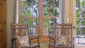 Dos mecedoras con cojines, ubicadas frente a una ventana con vistas a árboles.