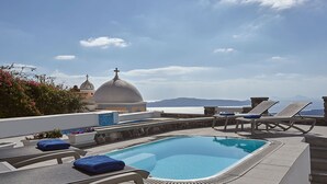 Pool på taget med liggestole og udsigt til kirke og bjerge.
