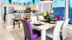 A modern kitchen with a central island, bar stools, and a dining table set for four.