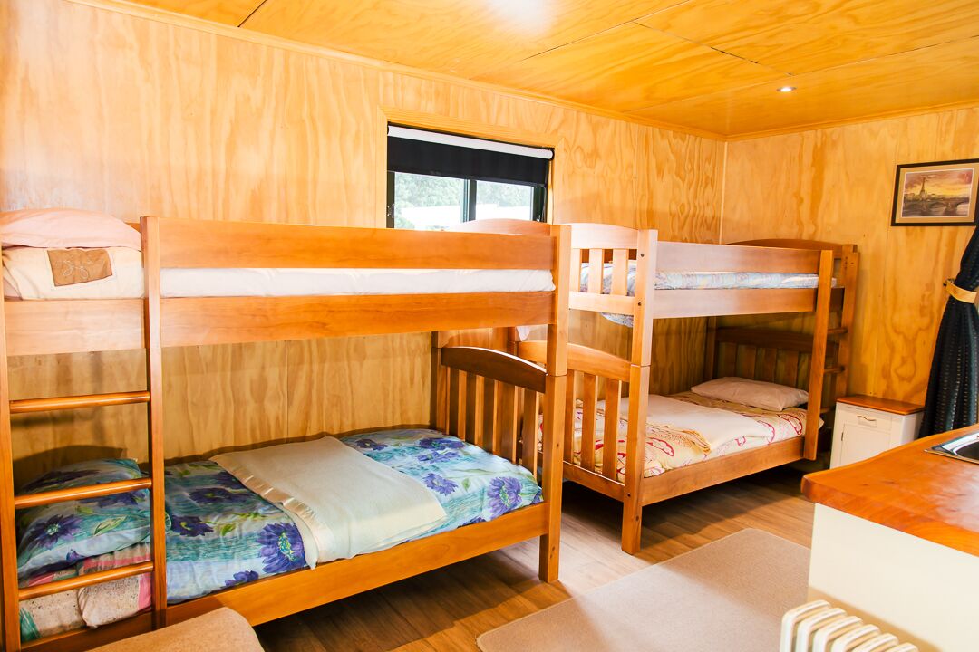 Una cabaña de madera con literas, una ventana y una pequeña kitchenette.