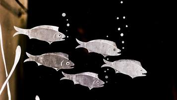 Siluetas de peces sobre un fondo oscuro.