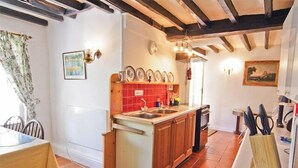 A compact kitchen with a central island, wooden cabinets, and a red tiled backsplash. - Group and Family Adventures in the Country Sleeps 19 (Machynlleth)
