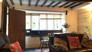 A cozy living room with a leather sofa, a wooden table, and a window with blinds. - Group and Family Adventures in the Country Sleeps 19 (Machynlleth)