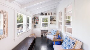 Quarto aconchegante com um banco de madeira, um sofá com almofadas estampadas e uma estante embutida.