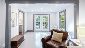 Um quarto amplo com um sofá de couro, um banco e uma mesa com abajur.