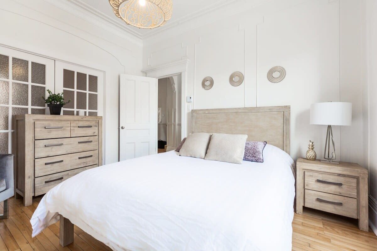 A bedroom with a large bed, wooden dresser, and bedside tables.