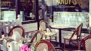 Ein Außenbereich mit Korbstühlen und Tischen vor einem Restaurant namens 'MANDY'S SALADES GOURMANDES'.