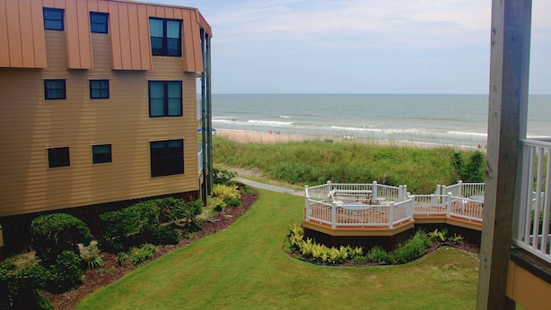 A residential building with a deck overlooking a beach. - Oceanfront! Topsail Dunes Beachfront Condo with Pool and Balcony (North Topsail Beach)