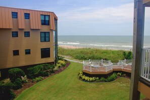 Ein Wohngebäude mit einer Terrasse mit Blick auf einen Strand.