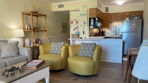A living room with a sofa, two armchairs, a coffee table, and a bookshelf. - Oceanfront! Topsail Dunes Beachfront Condo with Pool and Balcony (North Topsail Beach)